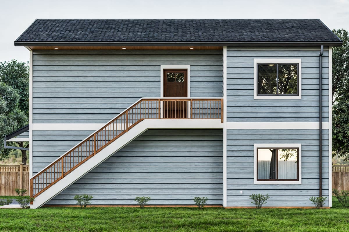 House plan exterior: Two-story home with blue horizontal siding, pitched roof, exterior staircase, and two windows.