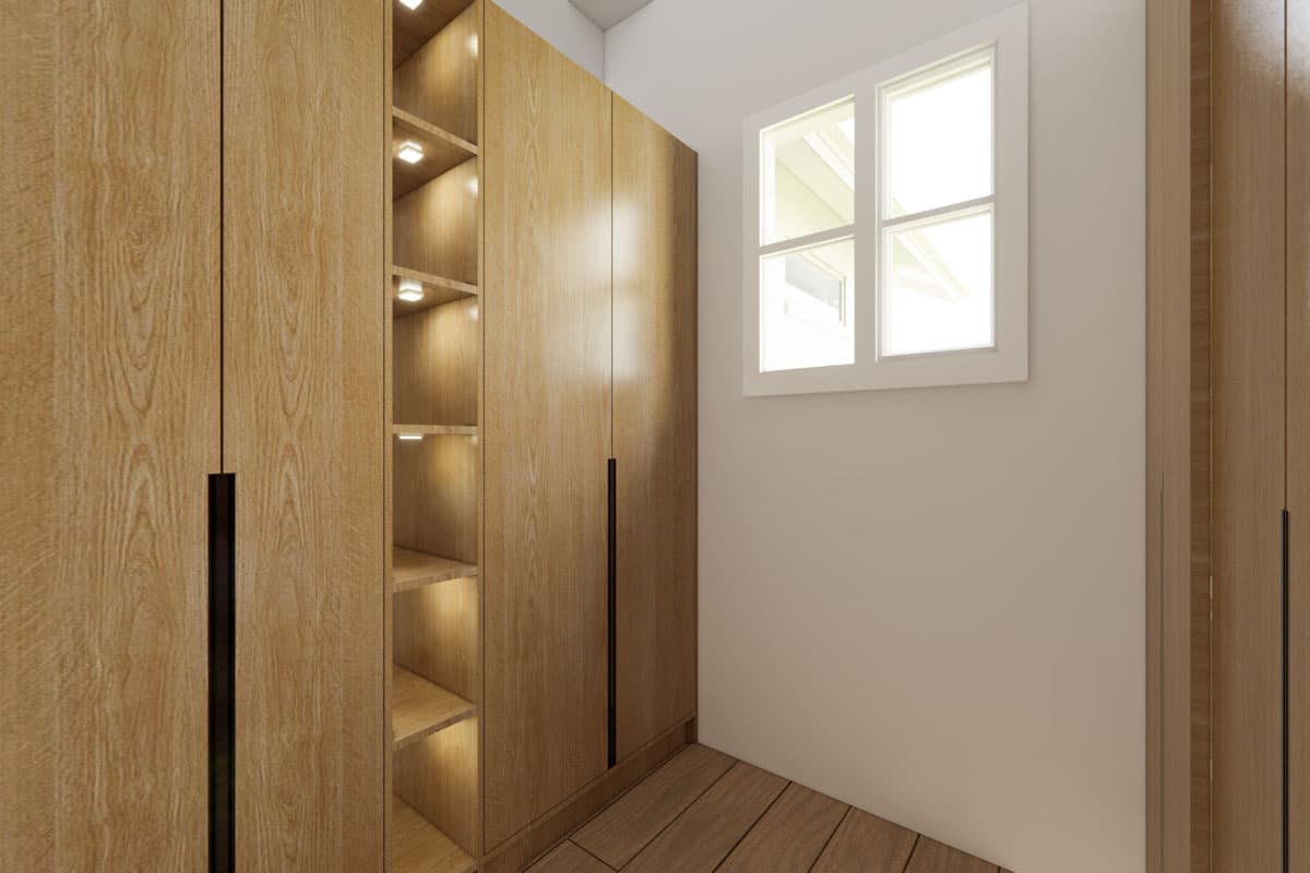 A walk-in coat closet with wooden cabinetry and open shelving illuminated by recessed lights. A window brightens the neutral-toned space.