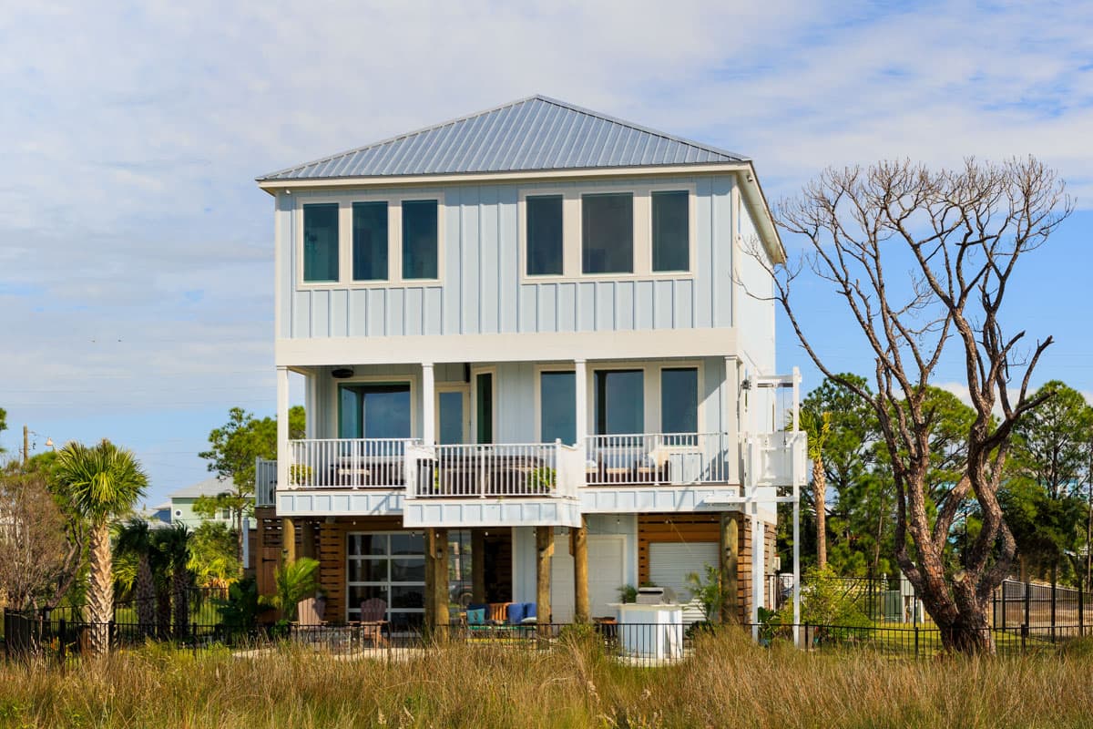 Coastal style house plan exterior. Two-story with metal roof, balconies, and elevated ground floor.