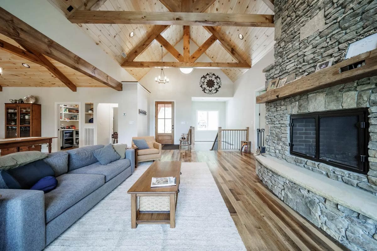 Great room interior with vaulted beamed ceiling, stone fireplace, and wood floors.