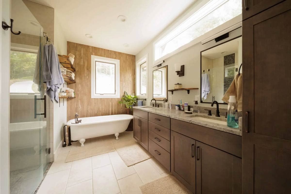 Bathroom with freestanding clawfoot tub, glass shower enclosure, and double vanity with dark wood cabinets.