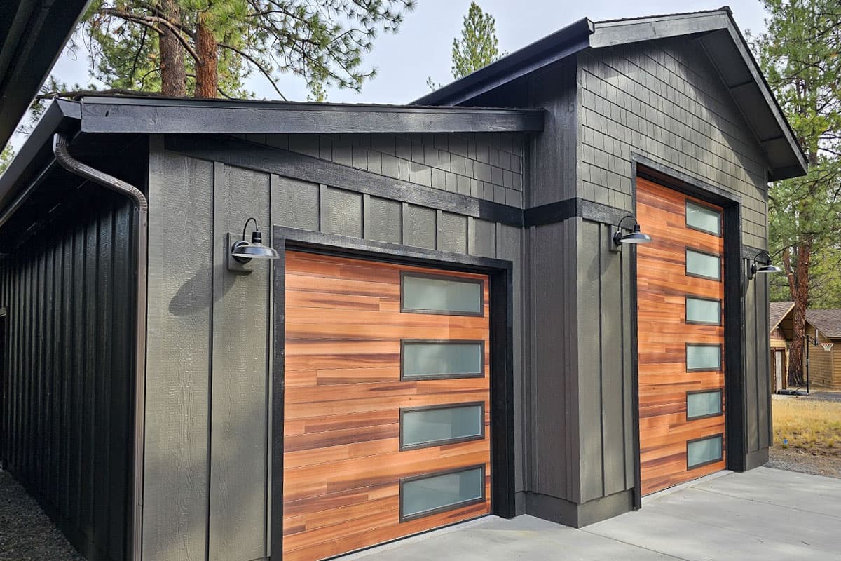 Modern garage exterior with horizontal wood doors featuring frosted glass panes and dark siding.