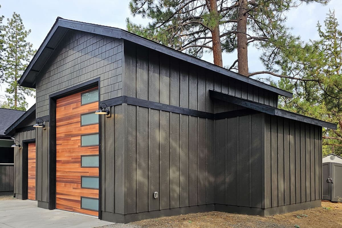 Modern garage exterior with wood slat doors, horizontal siding, and shingle gable.