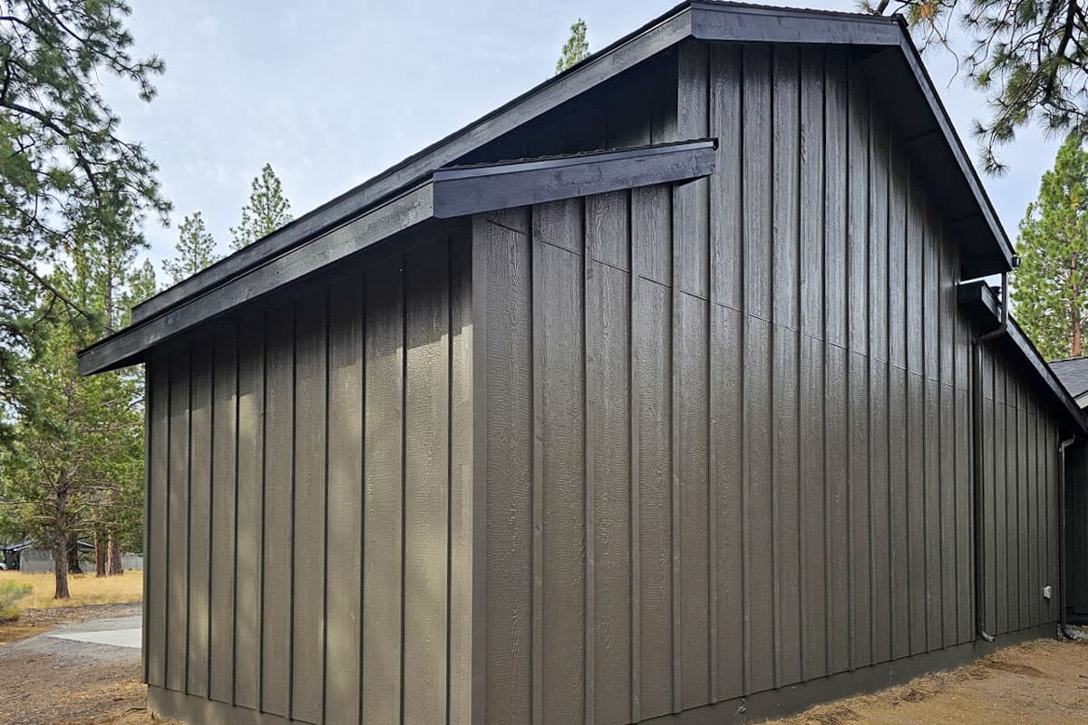 House plan exterior with vertical siding and a dark sloped roofline with exposed rafter tails.