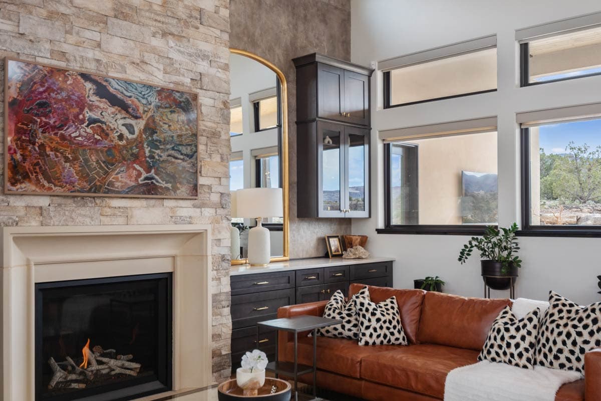 Interior living area with stone fireplace, leather sofa, built-in cabinetry, and large windows.