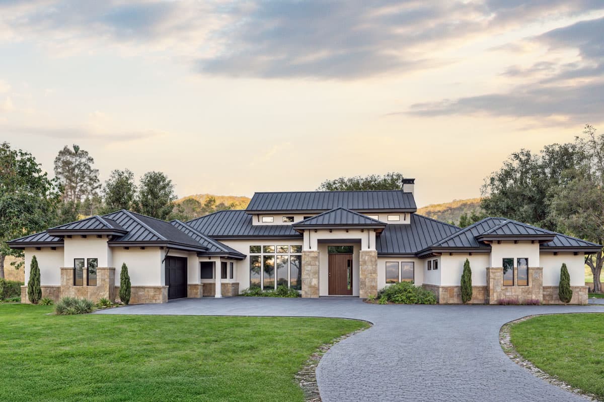 House plan exterior. Modern style, one-story home with a gabled roof, stone accents, and a covered entry. Includes a three-car garage.