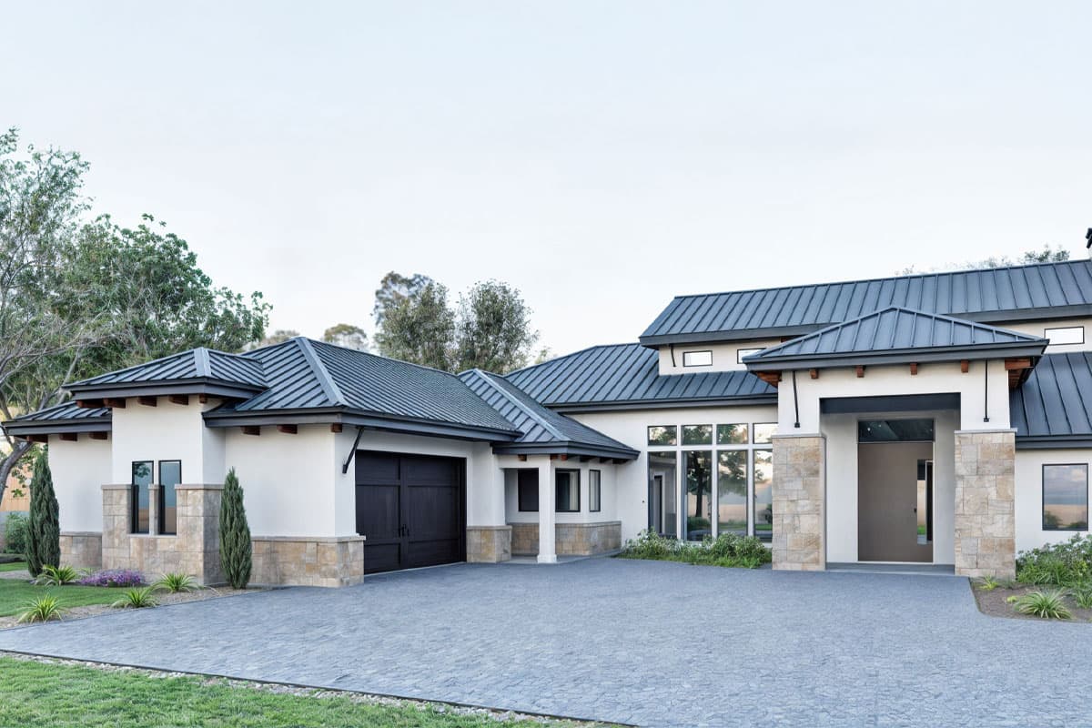 Modern house plan exterior with stucco walls, metal roof, stone accents, attached garage, and expansive windows.