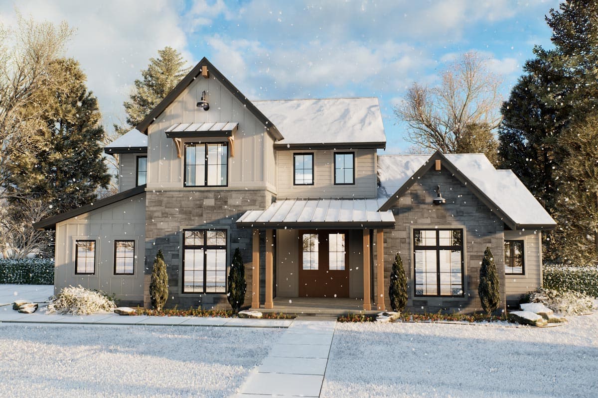 A two-story house with a snow-covered roof and porch. Snow falls gently on the lawn and surrounding trees, creating a cozy winter scene.