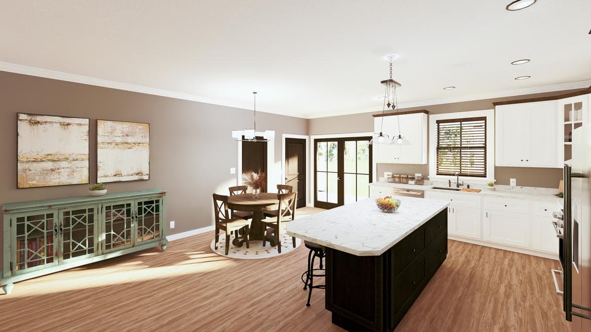 A modern kitchen with a large island and marble countertops. White cabinets and a dark-stained island and round dining table dominate the space.