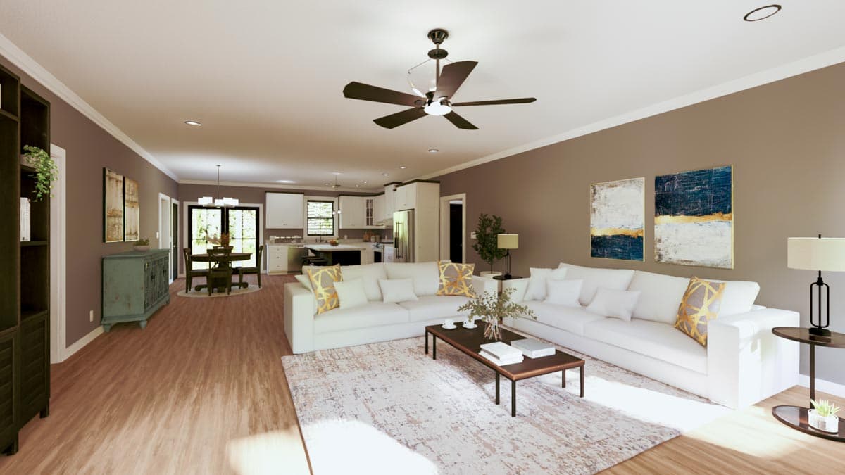 A modern, open-concept living space with a white sectional, coffee table, and area rug. The kitchen and dining area are visible in the background.