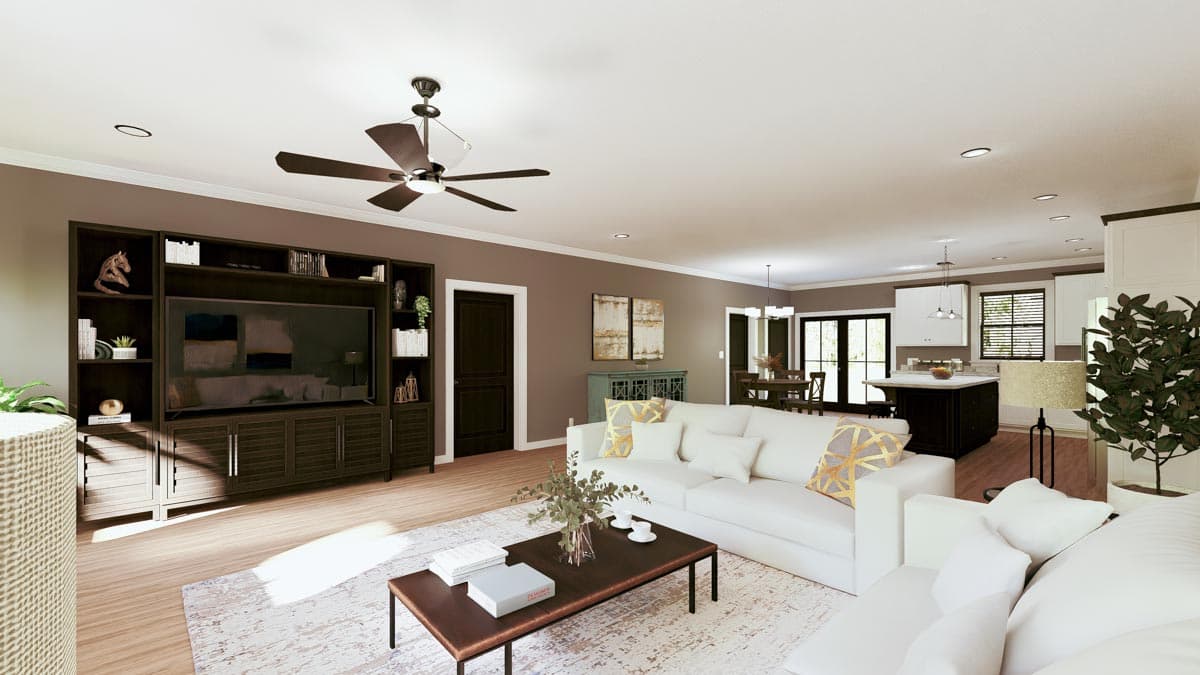 Spacious, modern living room with a white sofa, dark wood entertainment center, and open access to a kitchen area.