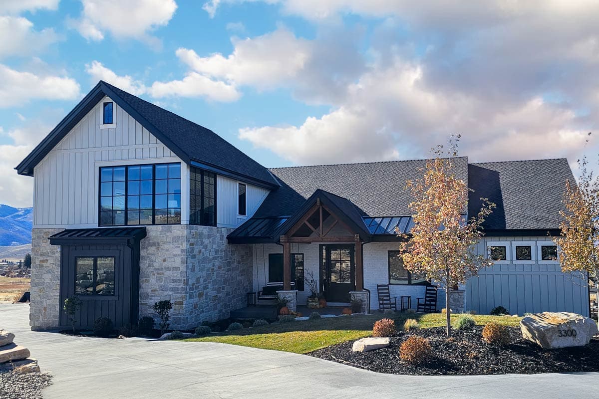 House plan exterior. Two-story Modern Farmhouse with board and batten siding, gable roof, and stone facade with large windows.