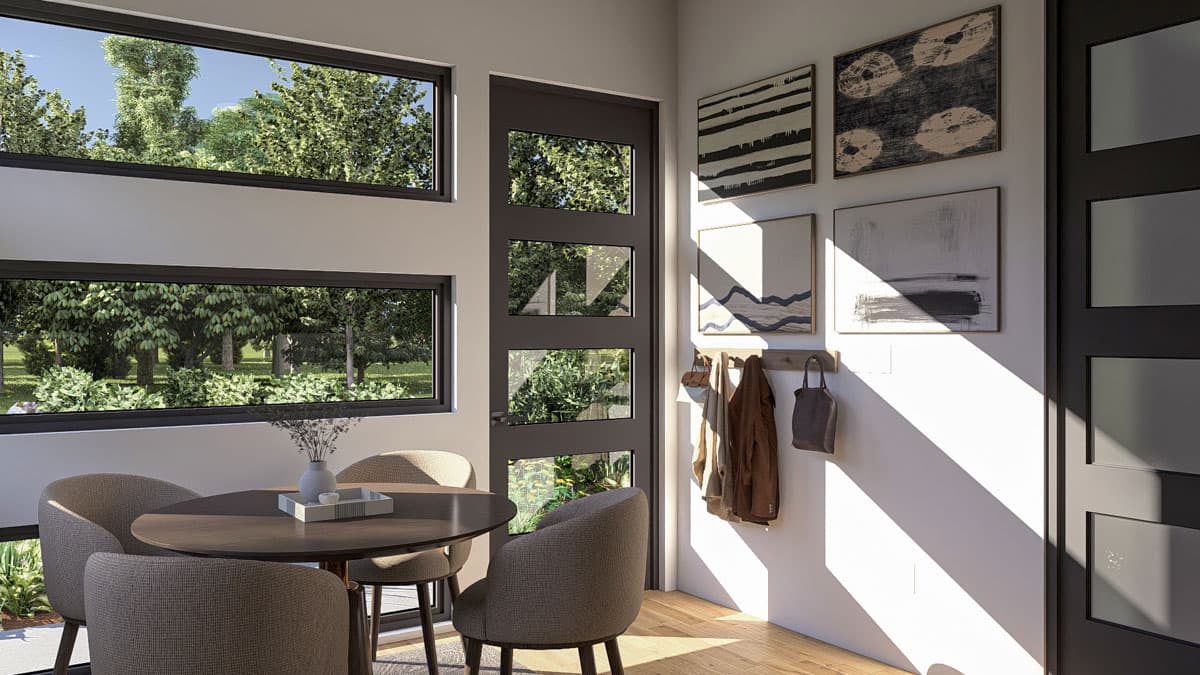 Dining area with round table and chairs, adjacent to a door with glass panels and large horizontal windows.