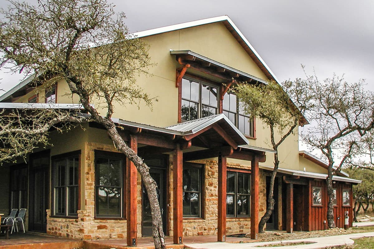 House plan exterior with stone and wood accents, two stories, metal roof, and covered porches.