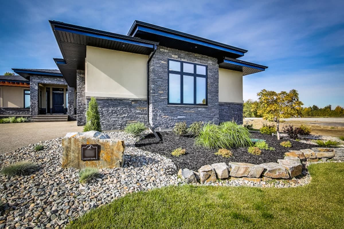 Modern house plan exterior with stacked stone, stucco, and sharp-angled rooflines.