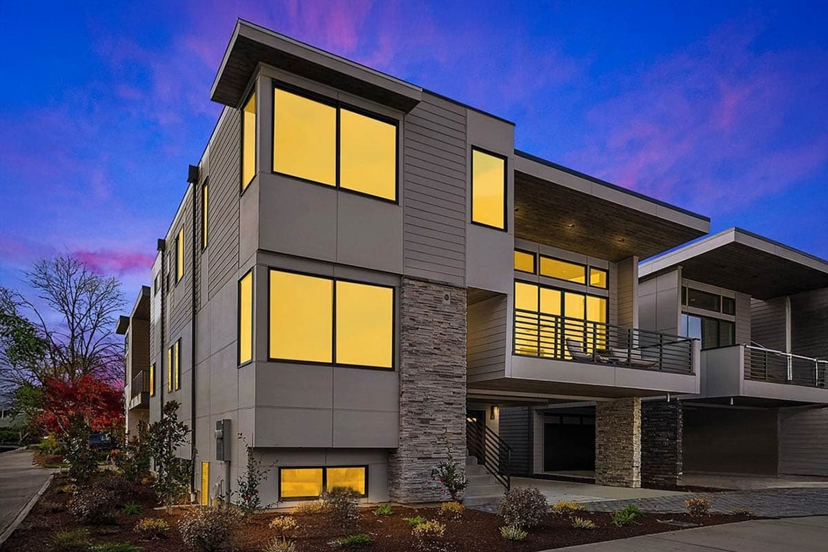 Modern house plan exterior with stacked stone accent, large windows, cantilevered balconies, and flat rooflines.