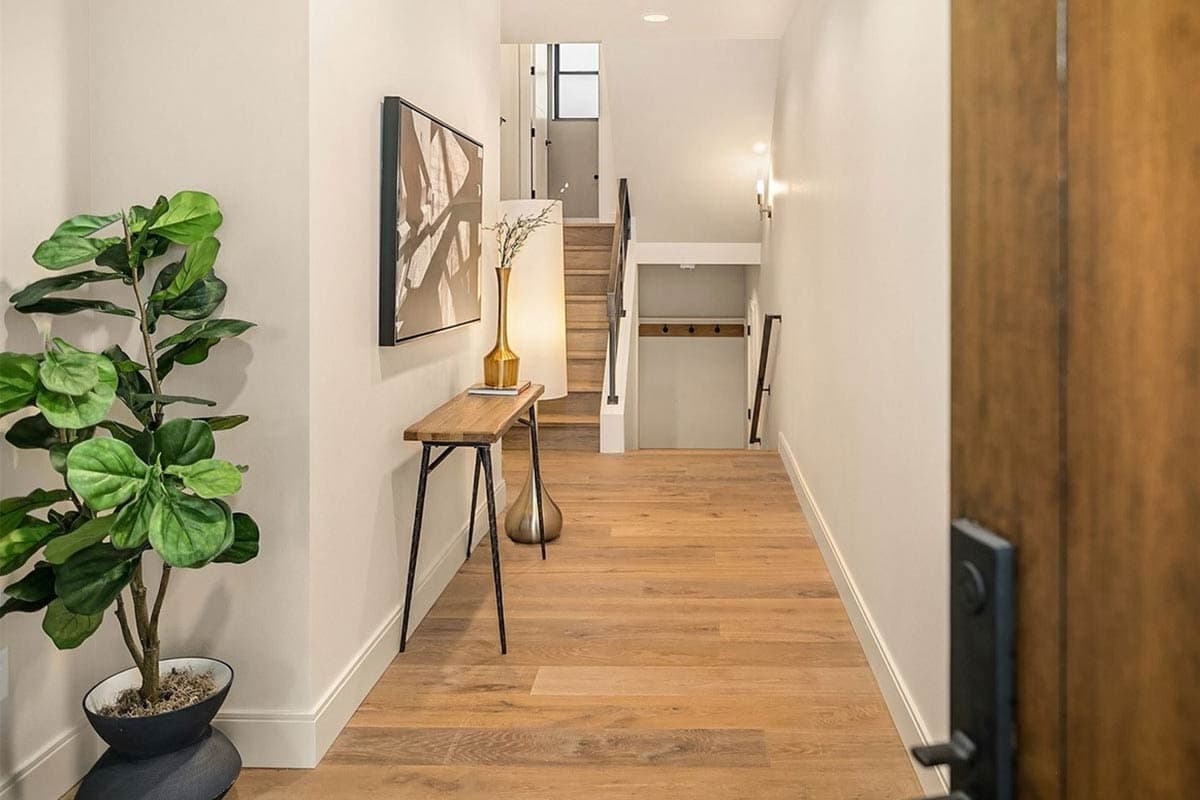 Hallway with wood floors, console table, stairs to upper level, and door to lower level.