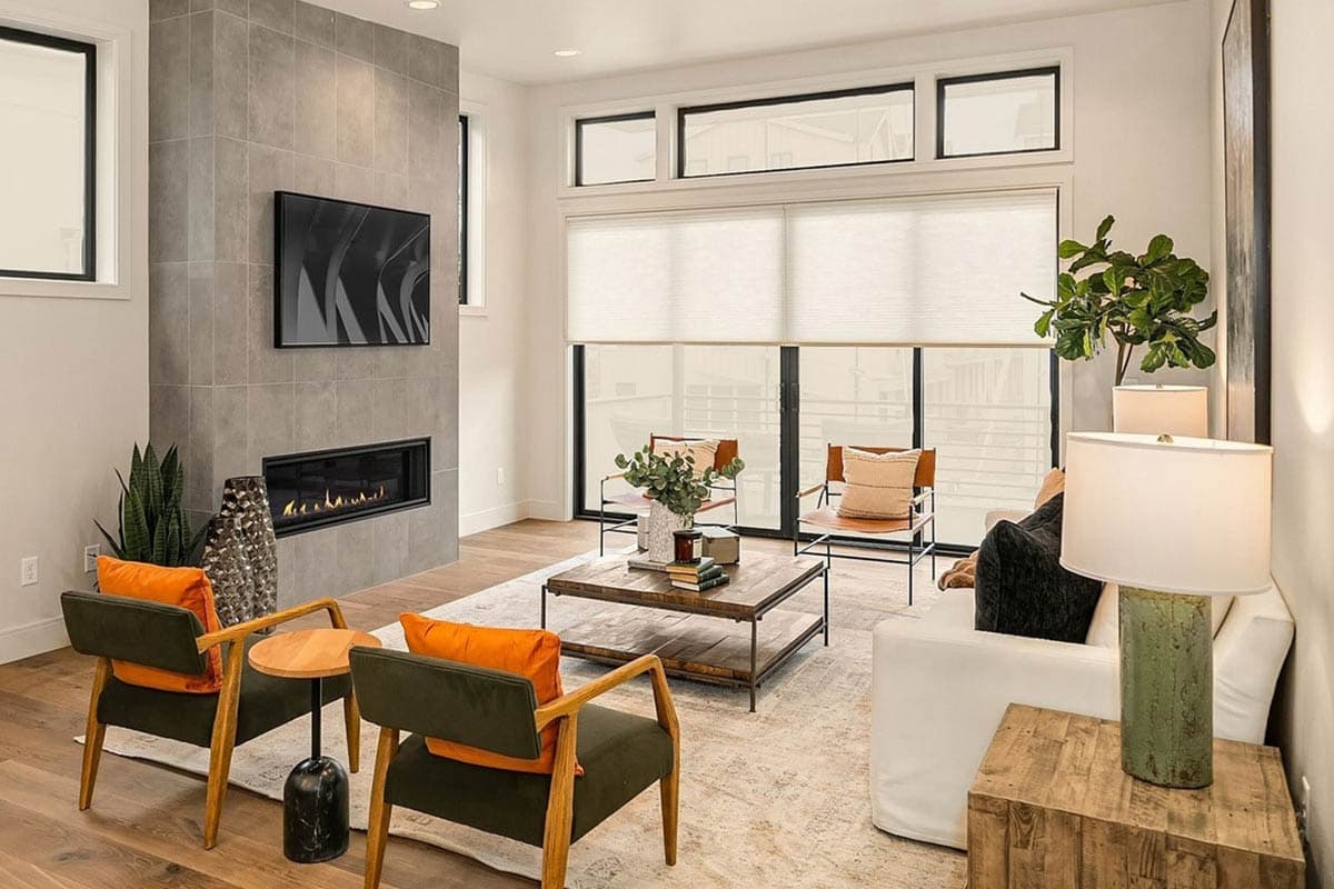 Living room featuring a linear fireplace with tile surround, mounted TV, large windows, and modern furniture.