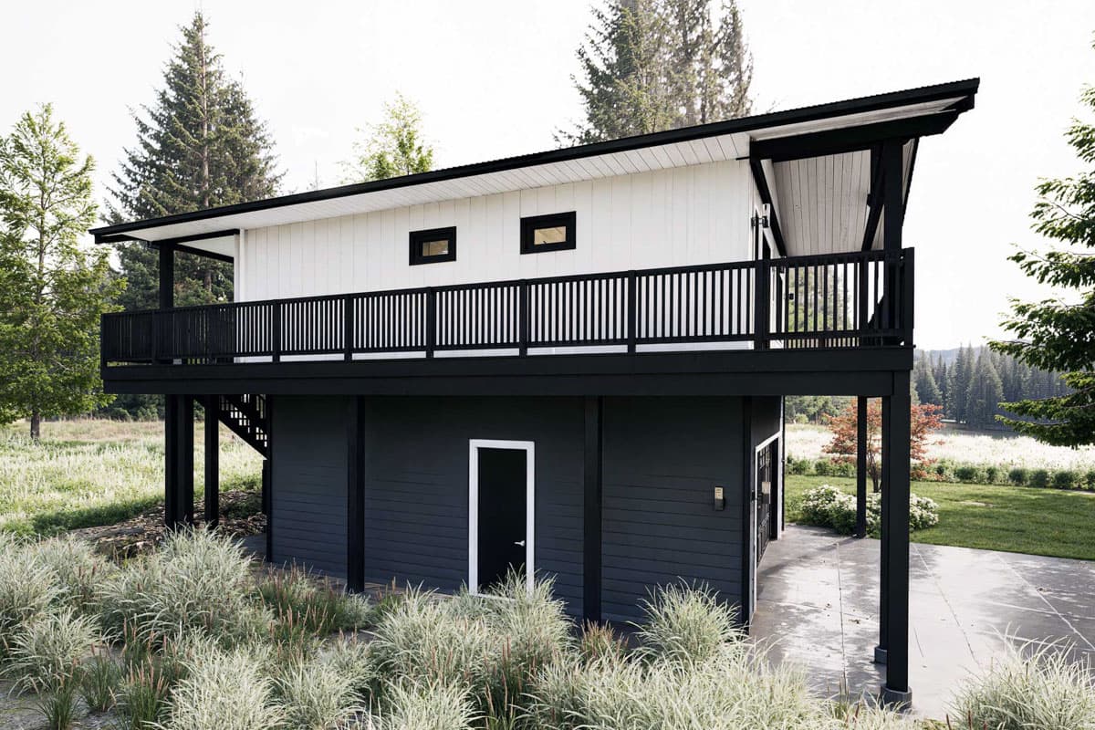 Modern house plan exterior with a cantilevered upper level, wrap-around deck, and dark-clad base.