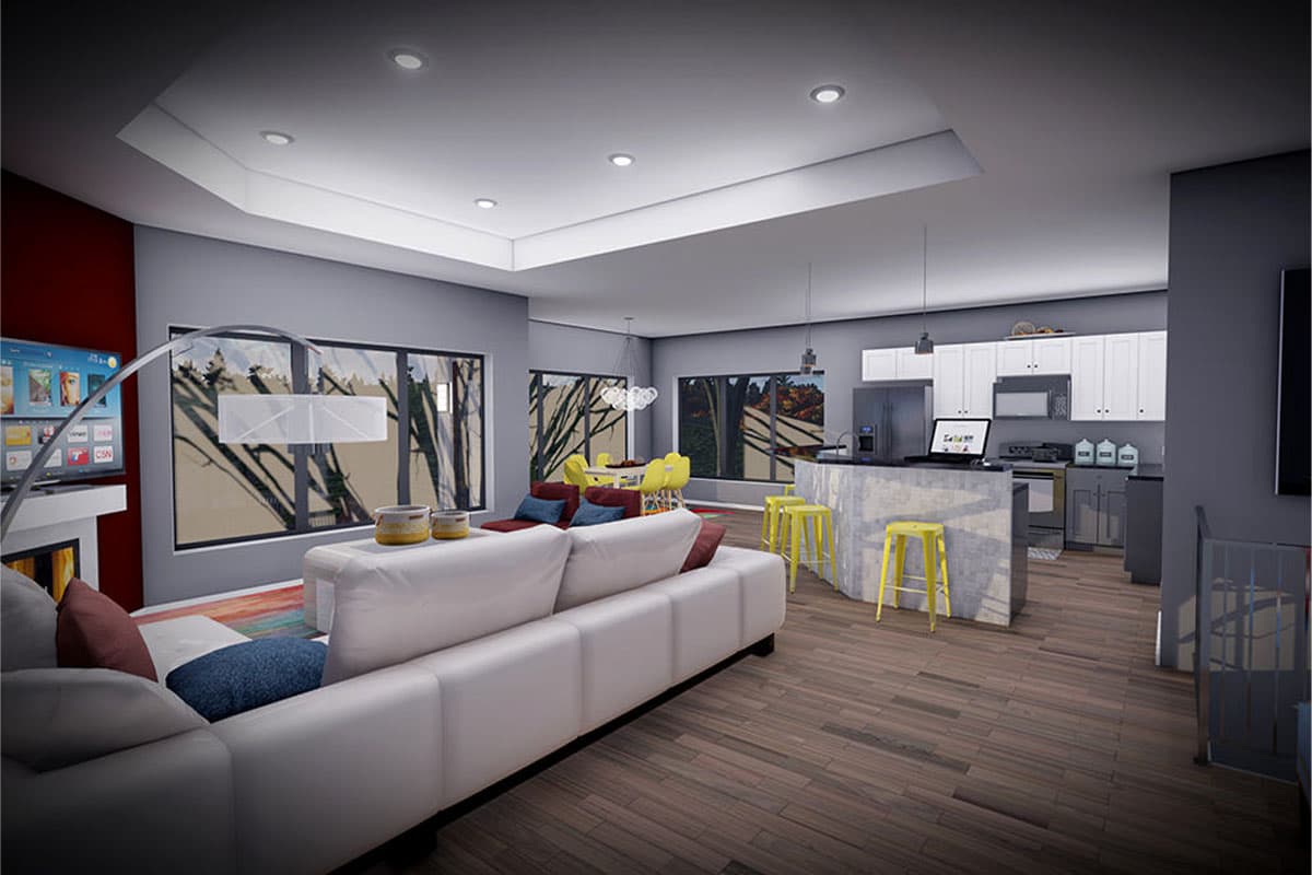 Open concept living area with white sectional sofa, dining set, and kitchen island with bar stools. Large windows overlook trees.