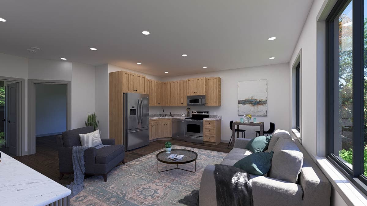 Open concept living area with a galley kitchen, stainless steel appliances, sofa, armchair, coffee table, and dining table.