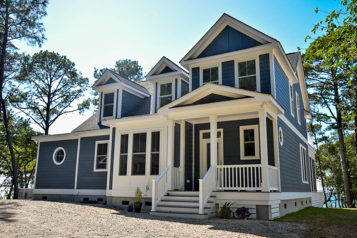 House plan exterior: two-story home with gabled dormers, a prominent front porch, and a circular window.
