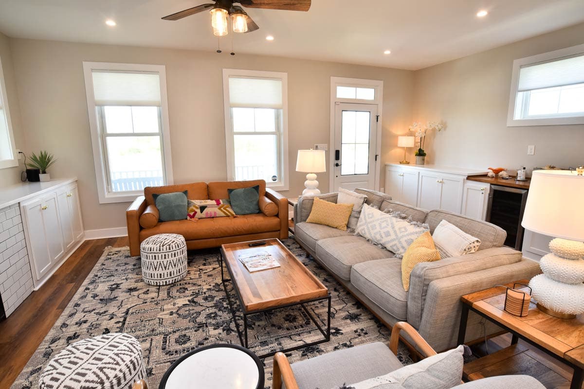 Living room with sectional sofa, leather sofa, built-in cabinetry, coffee table, and ceiling fan.