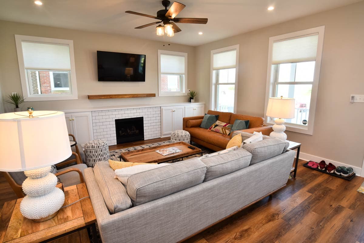 Interior view of a living room with a fireplace, built-in cabinets, two sofas, a coffee table, and a ceiling fan.