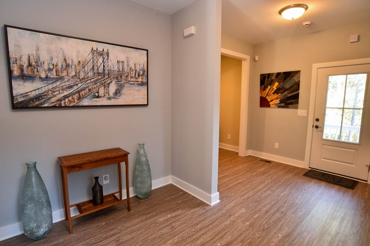 Interior view of a house entryway showing a console table, large artwork, and a door leading to another room.