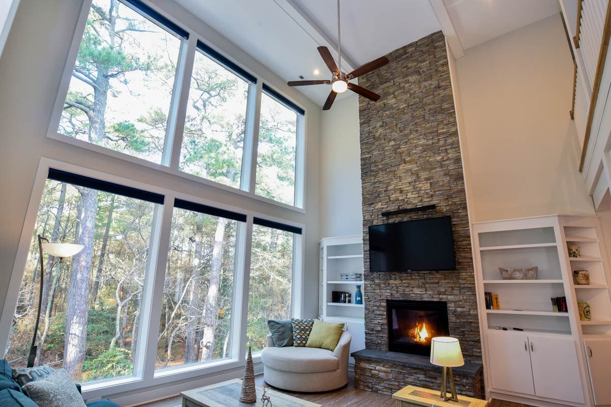 Great room with stone fireplace, vaulted ceiling, floor-to-ceiling windows, and built-in shelving.