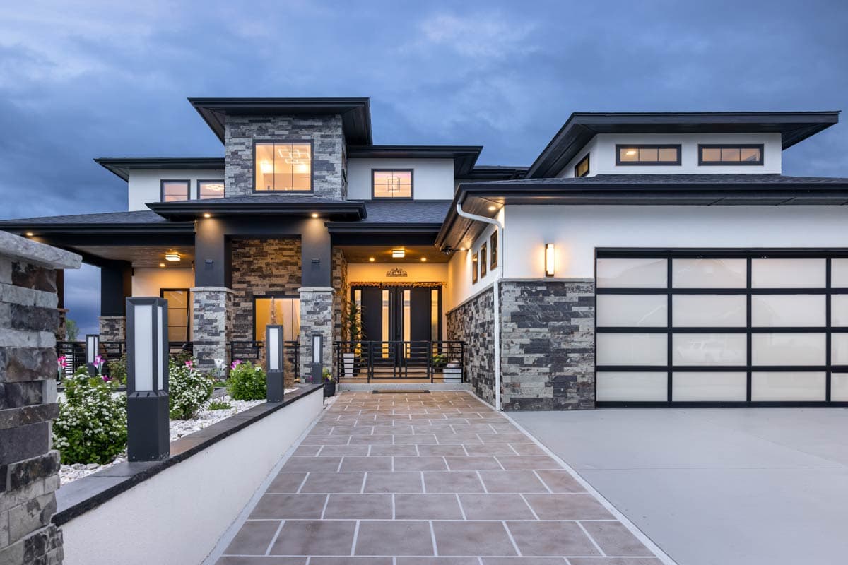Modern house plan exterior with stacked stone accents, flat rooflines, multiple gables, and a frosted glass garage door.