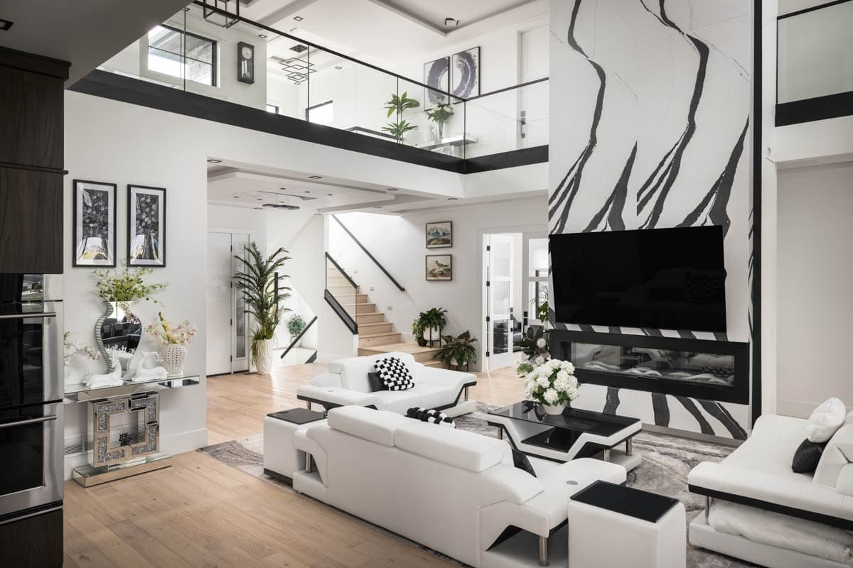 Great room with open-concept layout, vaulted ceiling, modern fireplace with abstract wall art, and a floating staircase with glass railing.