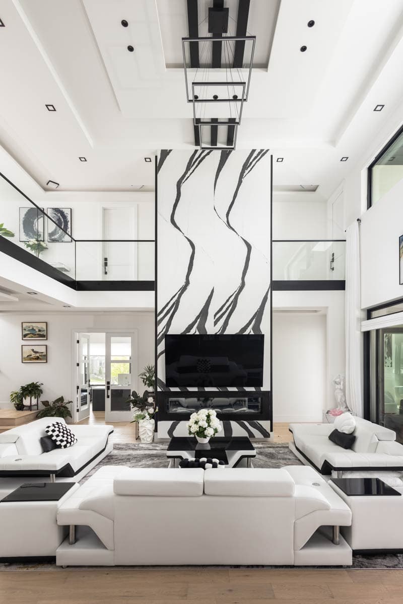 Great room with vaulted ceilings, floor-to-ceiling fireplace with abstract art, and contemporary white sofas.