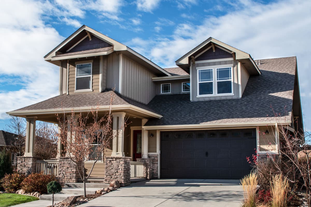House plan exterior. Two-story Craftsman home with a front porch supported by columns, gabled rooflines, and a two-car garage.