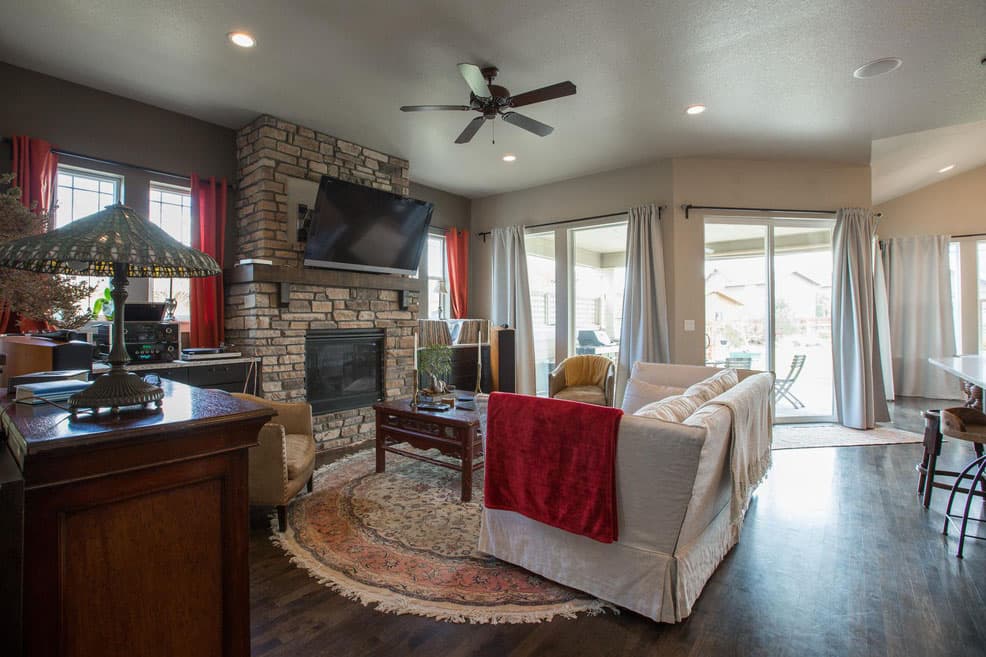 Great room interior featuring a stone fireplace with mounted television, sectional sofa, and sliding glass doors to outdoor space.