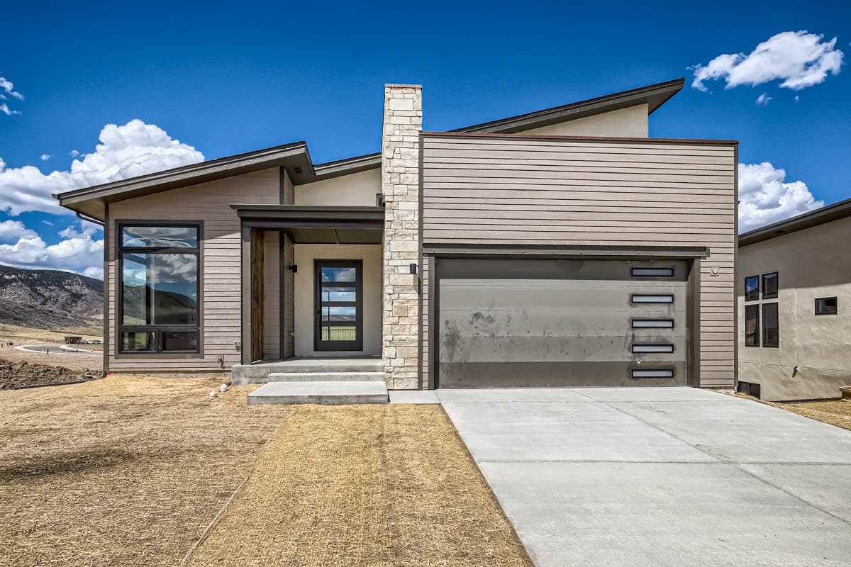 House plan exterior. Modern style, one-story home with a flat roof and shed rooflines, a covered entry, and a side-entry garage.