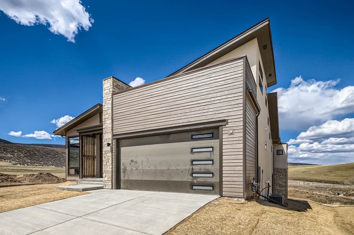 House plan exterior with modern style, stone accents, horizontal siding, and multi-pane garage door.