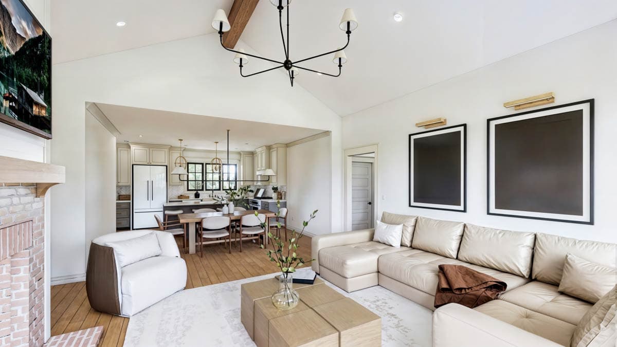 Open concept living room and kitchen with vaulted ceilings, exposed beam, sectional sofa, fireplace, and kitchen island.