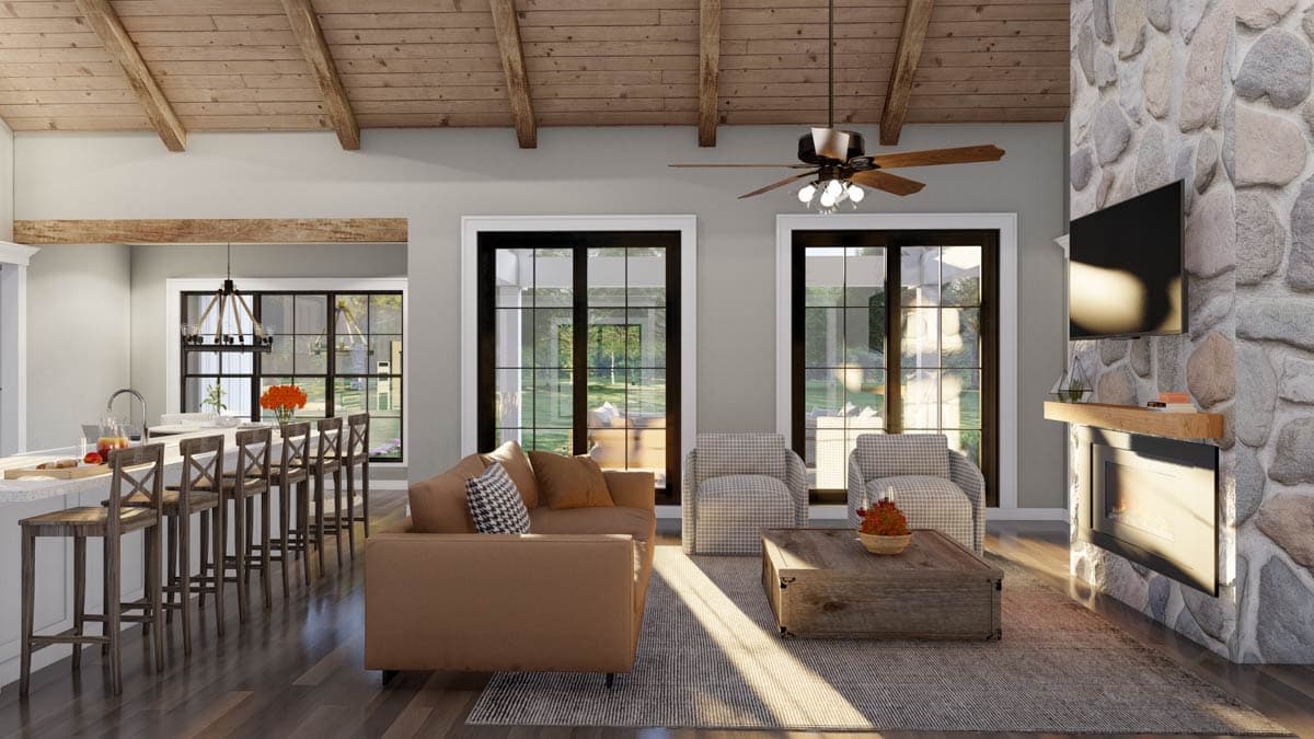 Great room with vaulted wood-beamed ceiling, stone fireplace, kitchen island with bar seating, and large windows.