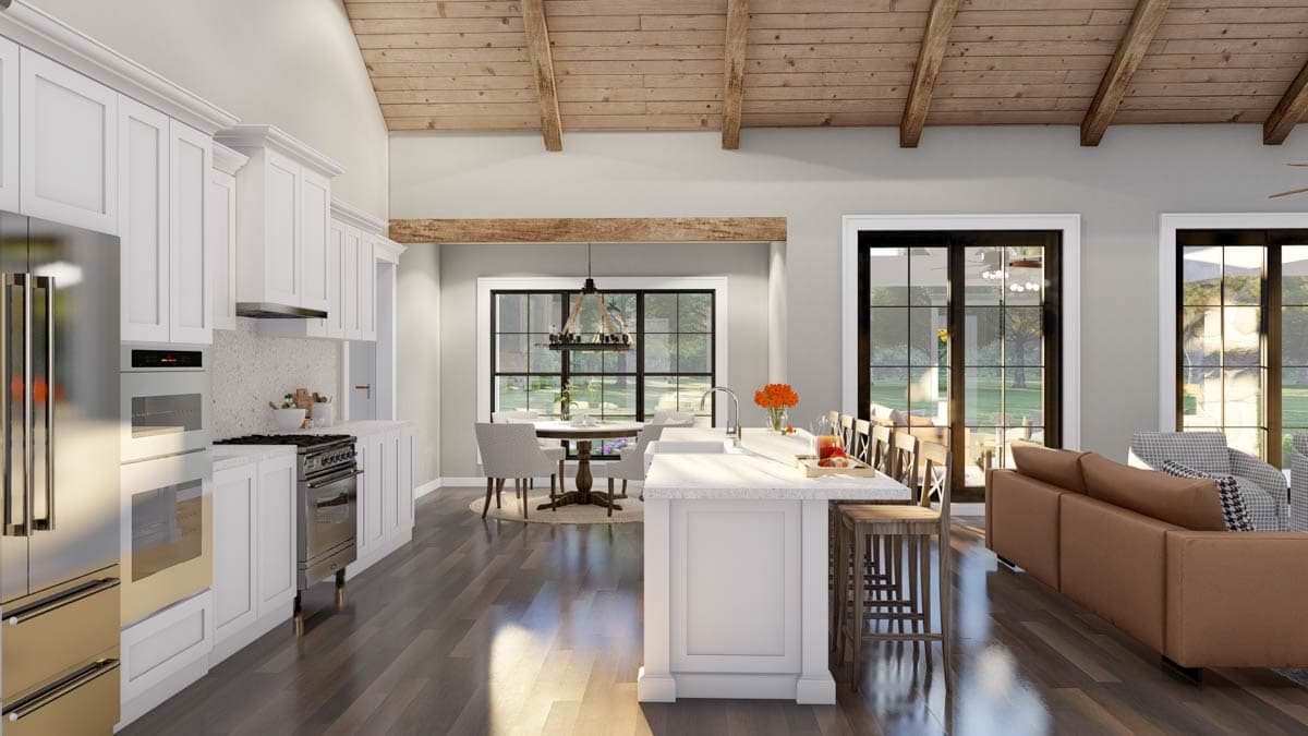 Open concept living area with vaulted wood beam ceiling, white kitchen cabinets, island, dining area, and living room with large windows.