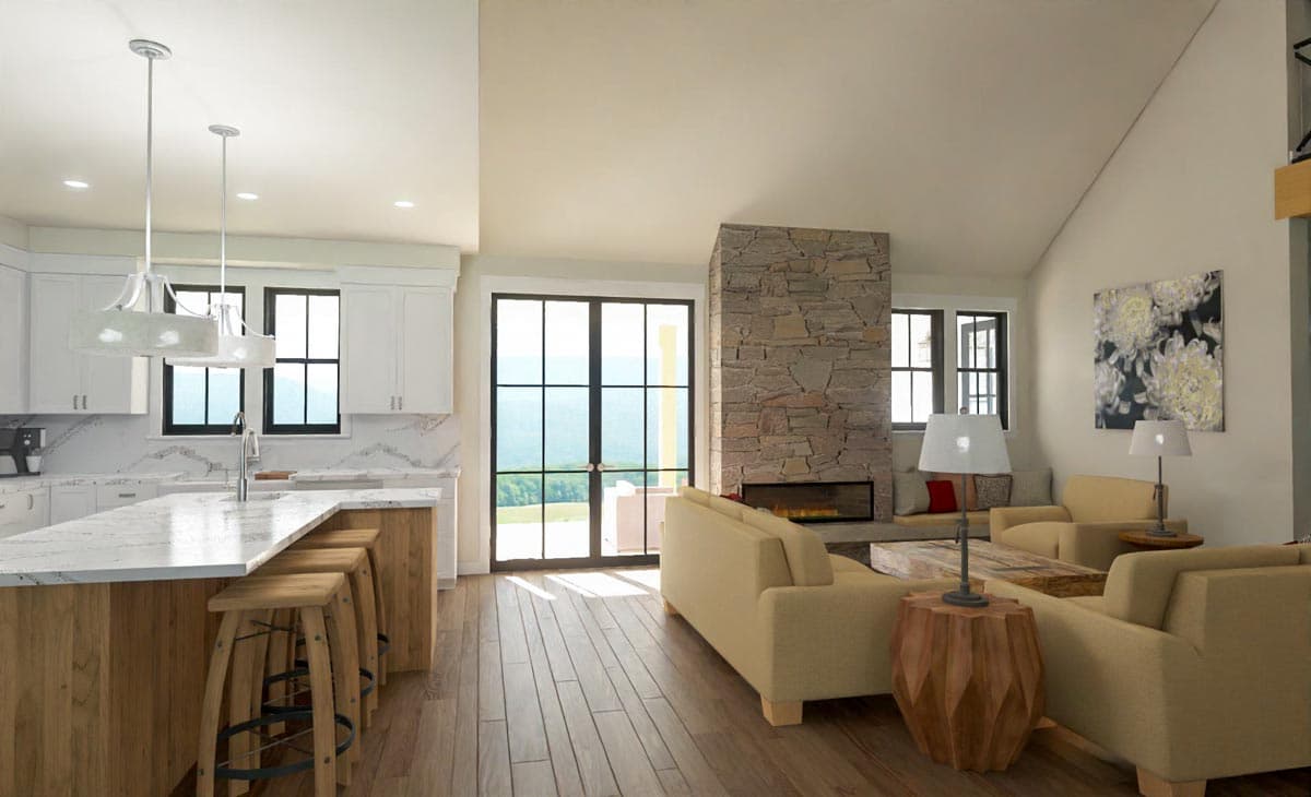 Open-concept living space with a stone fireplace, light wood floors, and kitchen island. Large windows overlook a scenic view.