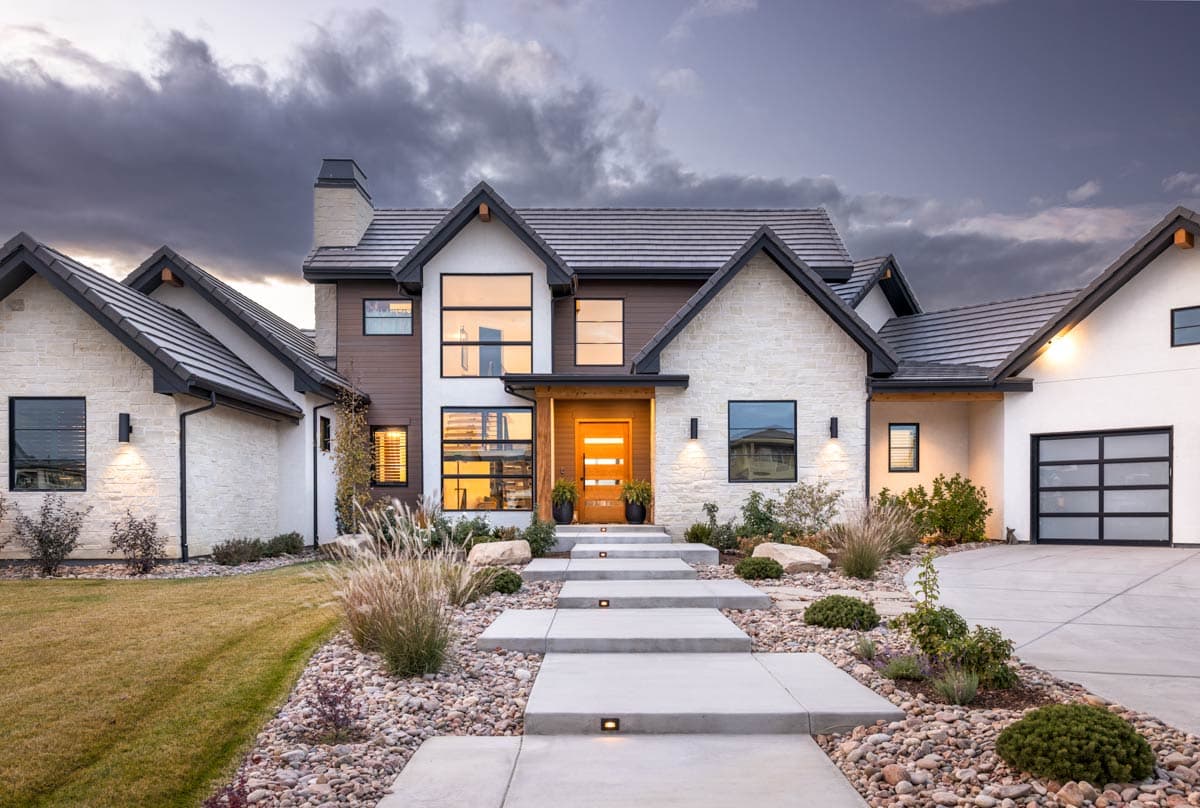 Modern house plan exterior with stone and wood facade, prominent gables, metal roof, and large windows.