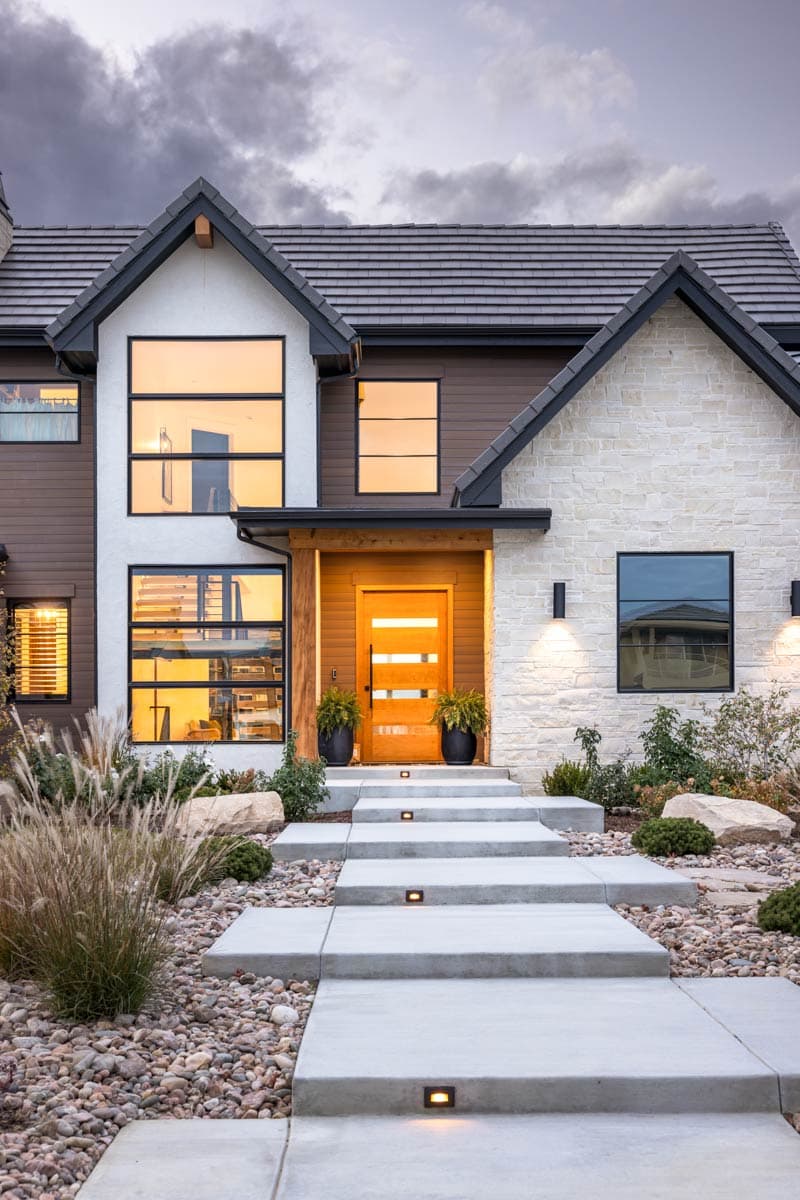 Modern house plan exterior with a two-story design, large vertical windows, stone accents, and a wooden entry.