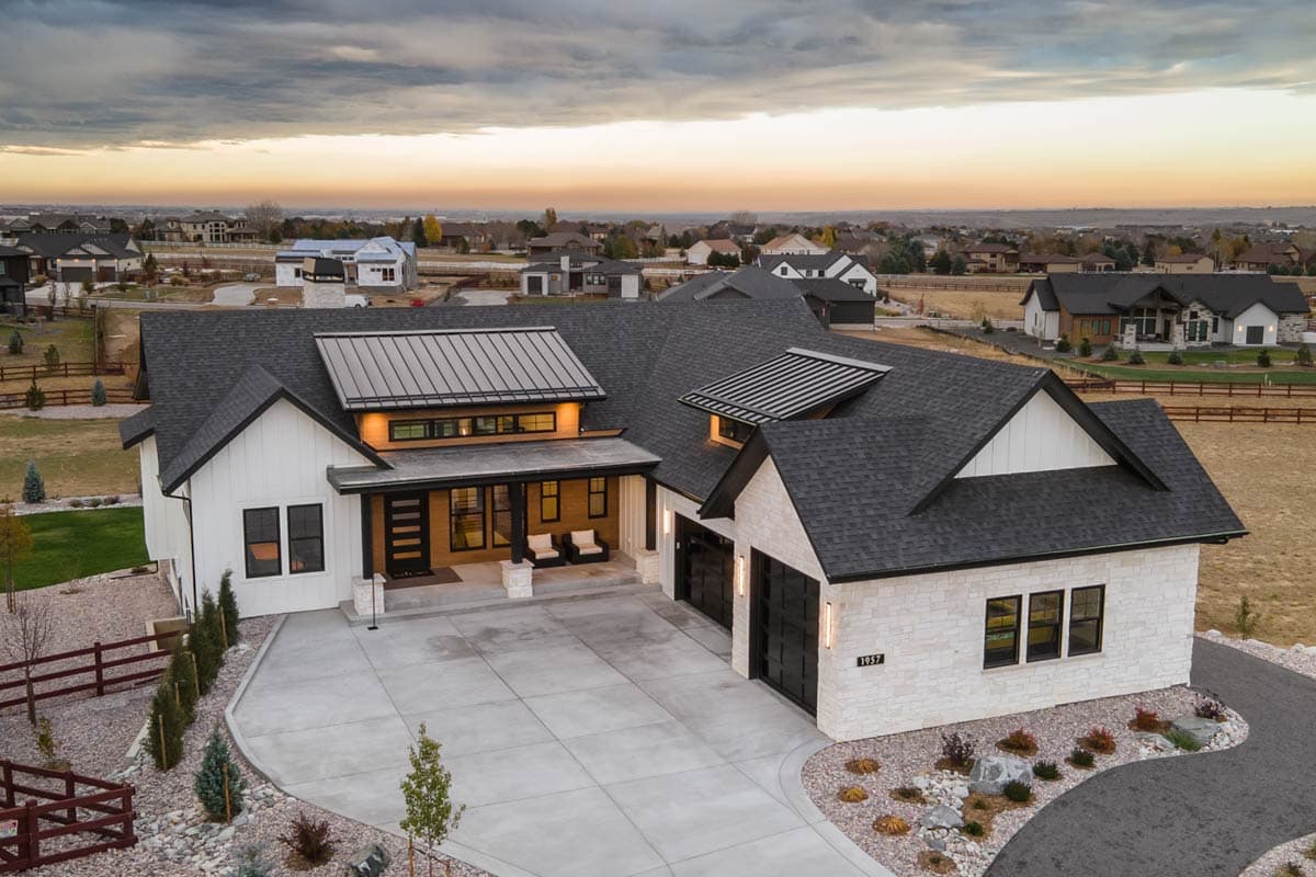 House plan exterior. Modern farmhouse style with 1 story, metal roof accents, covered porch, and attached garage. Stone and siding exterior.