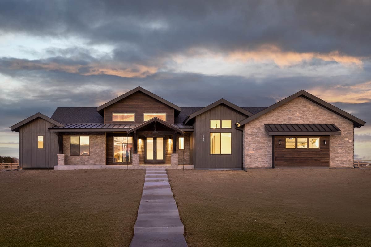 House plan exterior. Ranch style with multiple gables, stone veneer accents, and a covered front porch. Features include a dark roof and siding.