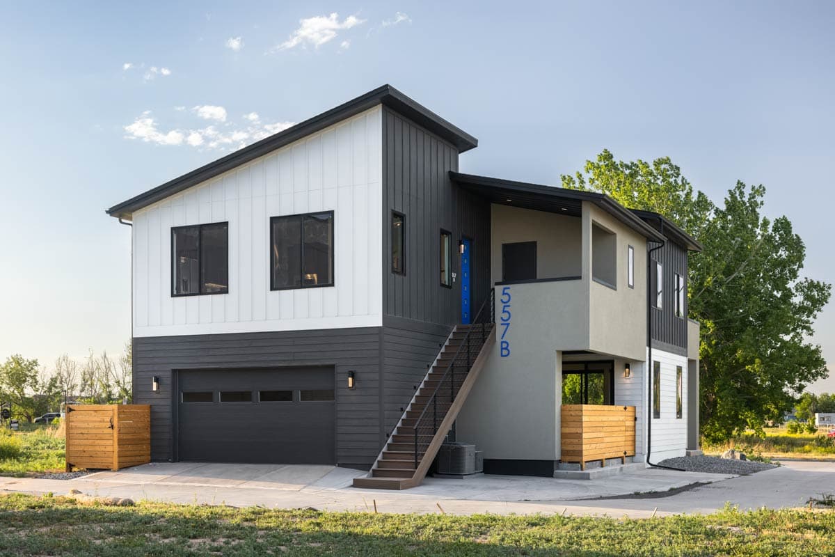Modern house plan exterior with vertical siding, a two-car garage, and an elevated exterior staircase.
