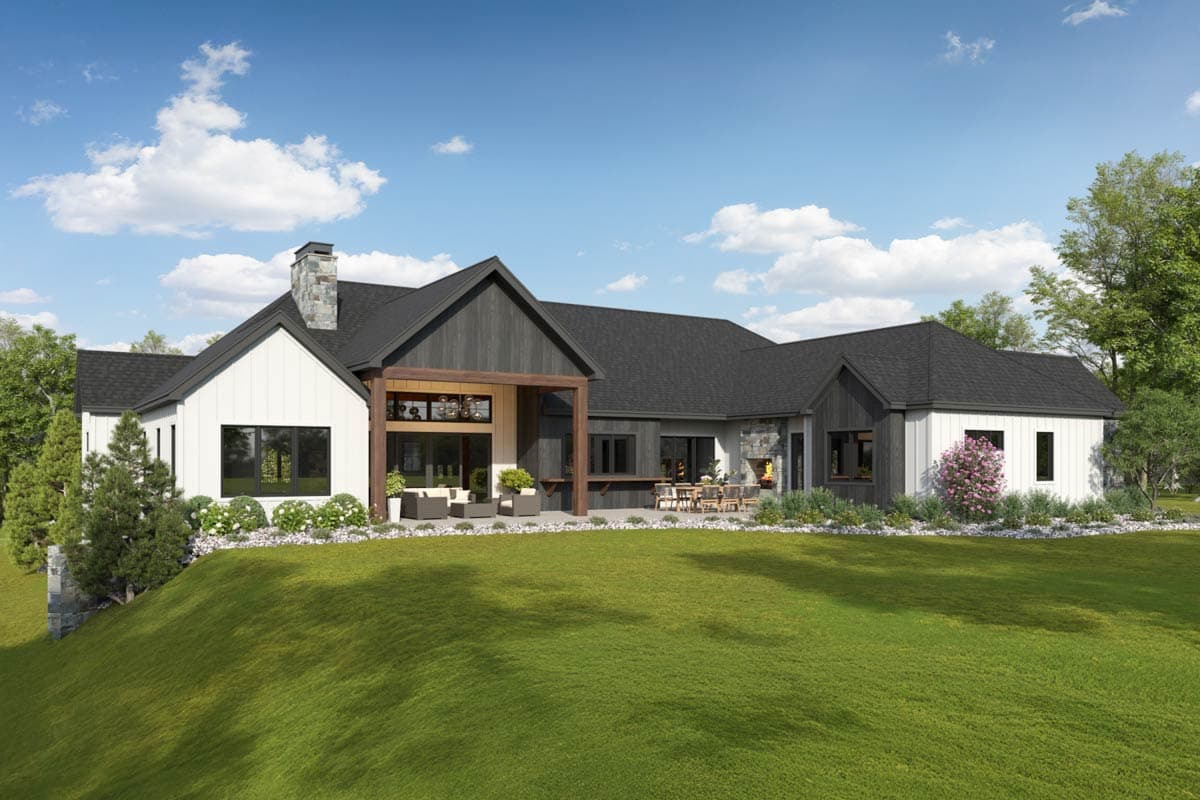 Modern Farmhouse house plan exterior with white board-and-batten and dark wood siding, covered patio with outdoor fireplace, and stone chimney.