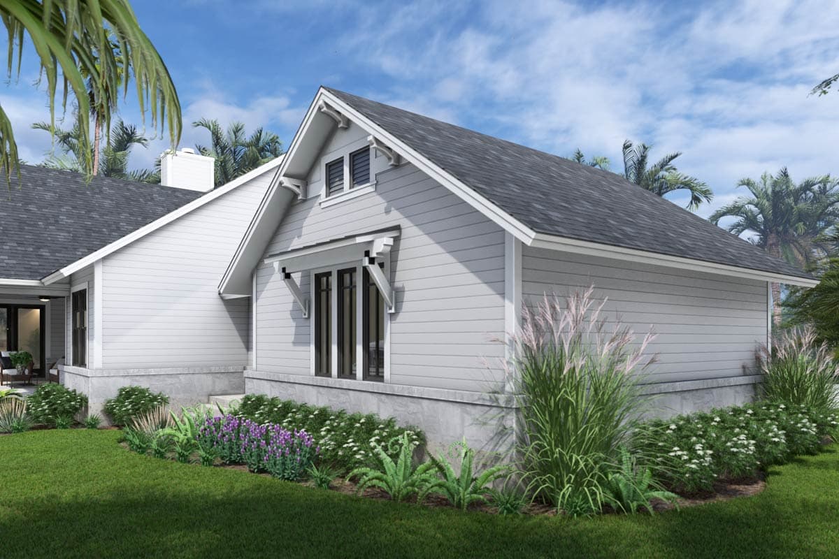 A modern, light gray house with dark trim and a gabled roof. Landscaping with lush green grass, plants, and palm trees sets the tropical scene.