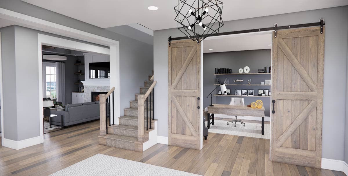 Interior view showing a living room with fireplace and stairs, opening to a home office with barn doors.