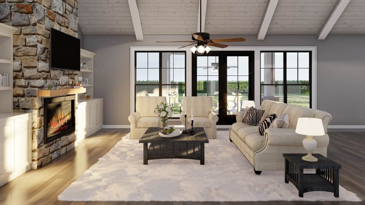 Living room with stone fireplace, vaulted wood-beamed ceiling, and french doors opening to a patio.